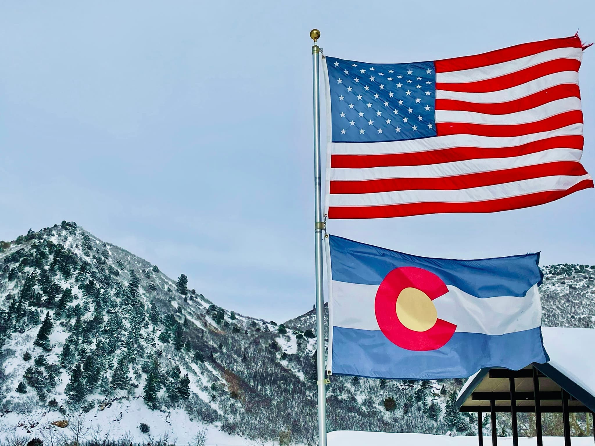 us and colorado state flags with snowy mountains in the background